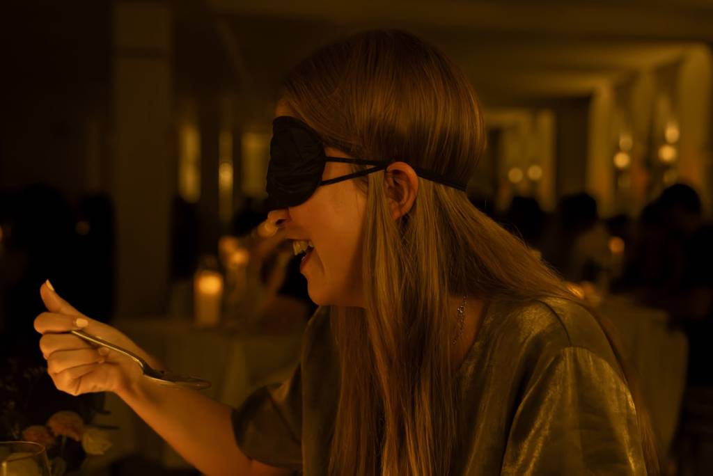 A blindfolded woman holding her fork at a Dining in the Dark experience