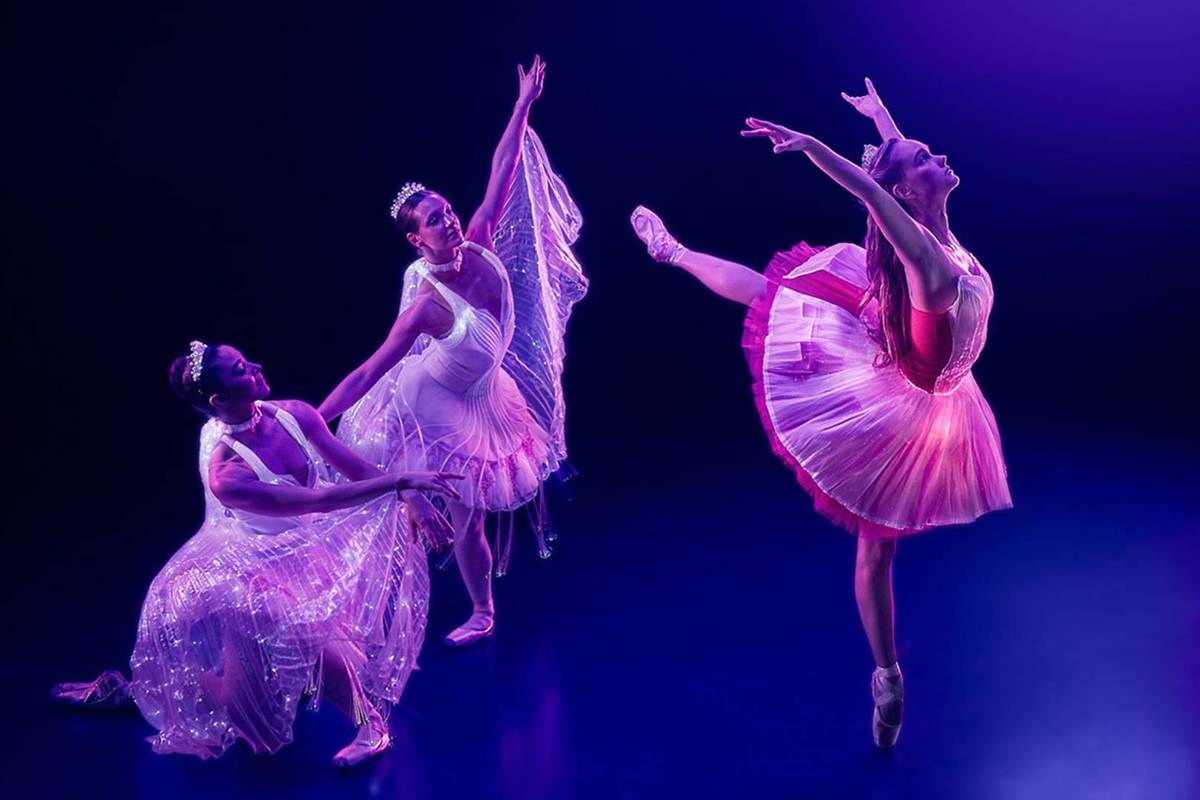 Three ballerinas wearing luminous pink outfits and dancing at Ballet of Lights
