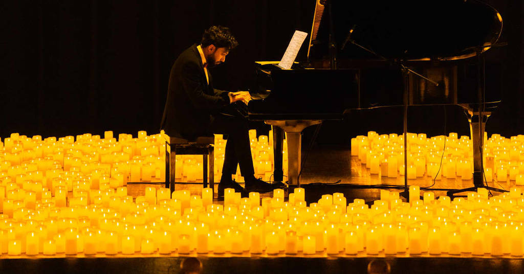 A pianist performing amid a sea of candles