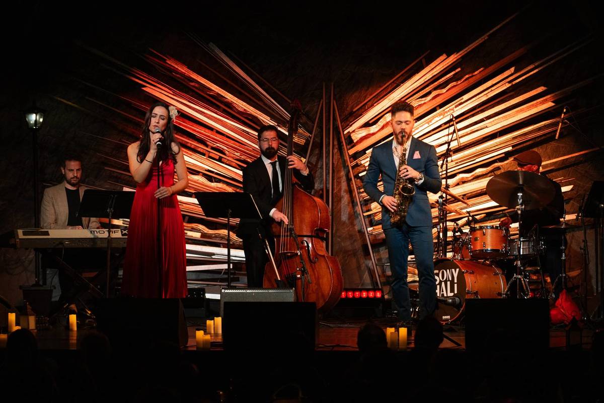 Fünf Musiker und eine Sängerin stehen auf der Bühne von "We call it Jazz" und performen zusammen einen Song. Die Beleuchtung ist stimmungsvoll und auf dem Boden stehen einige Kerzen.