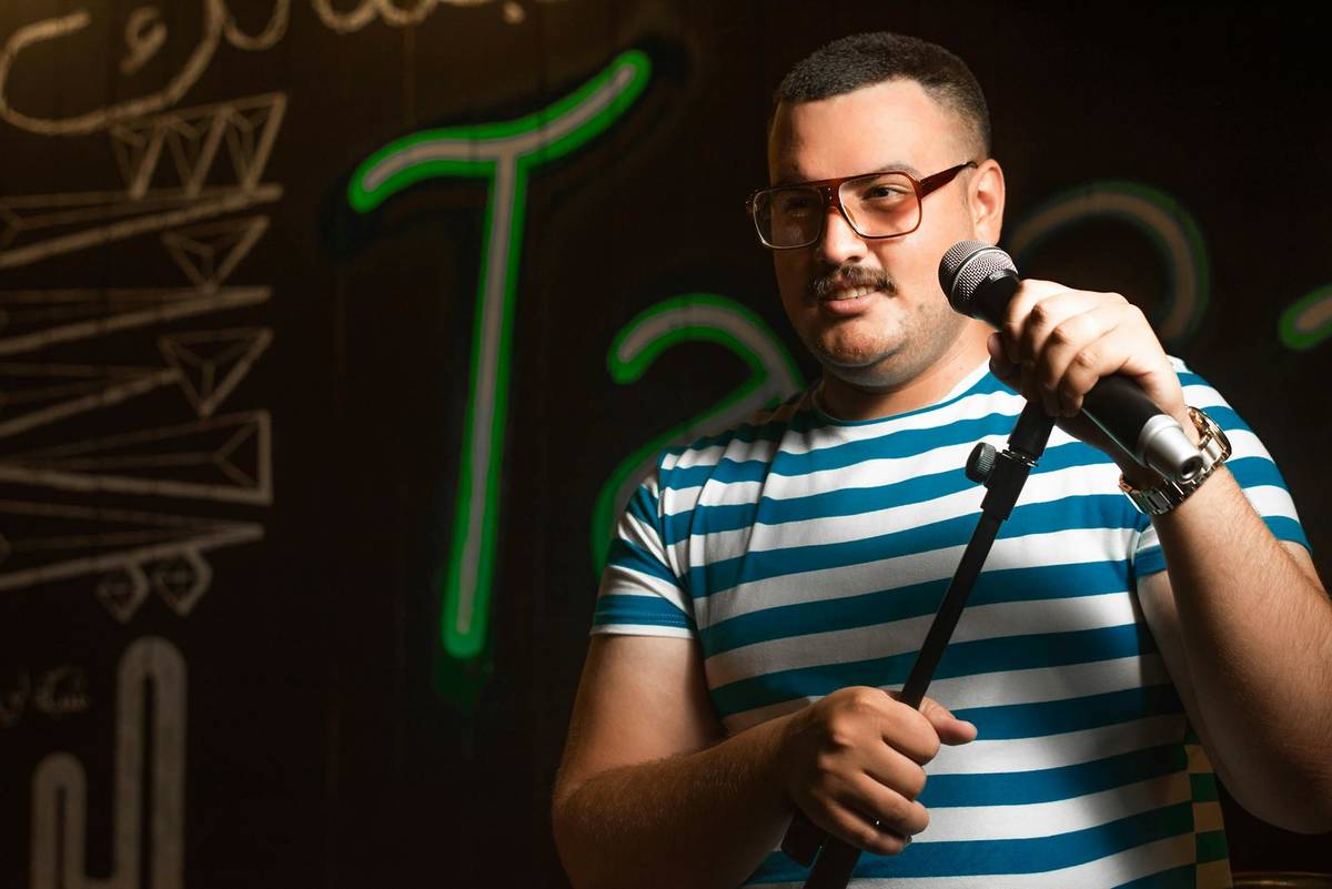 Stand Up Comedian steht mit einem Mikrofon in der Hand auf der Bühne