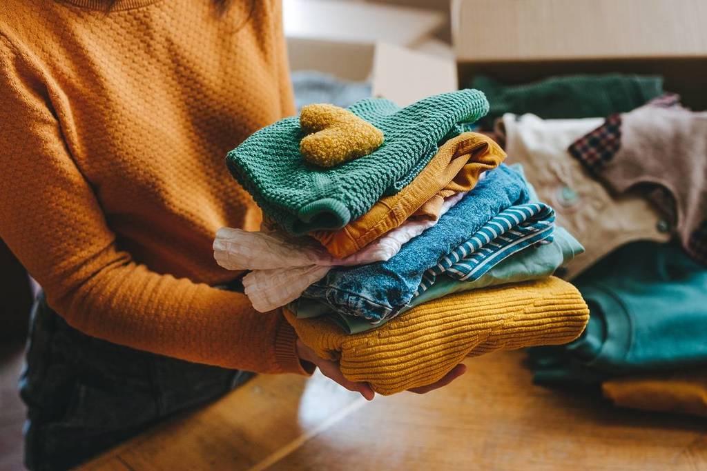 Una donna tiene in mano una pila di vestiti