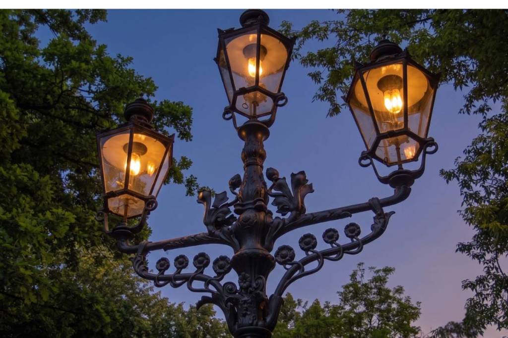 A glowing three-flame gas lantern against a blue evening sky. An atmospheric photo opportunity for an evening stroll through Berlin’s Tiergarten.