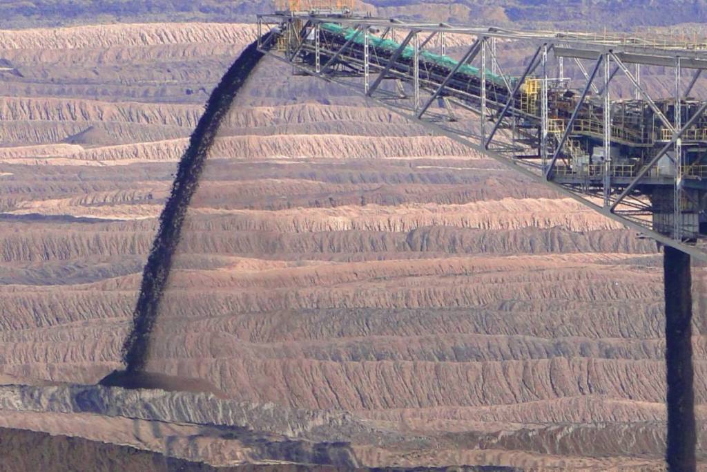 Gli strati di terra a gradini e le terrazze in una miniera di lignite a cielo aperto ancora in attività nella Lusazia, che mostrano le diverse sfumature di colore e le texture del terreno. Davanti, una gru che sta scaricando nuova terra.