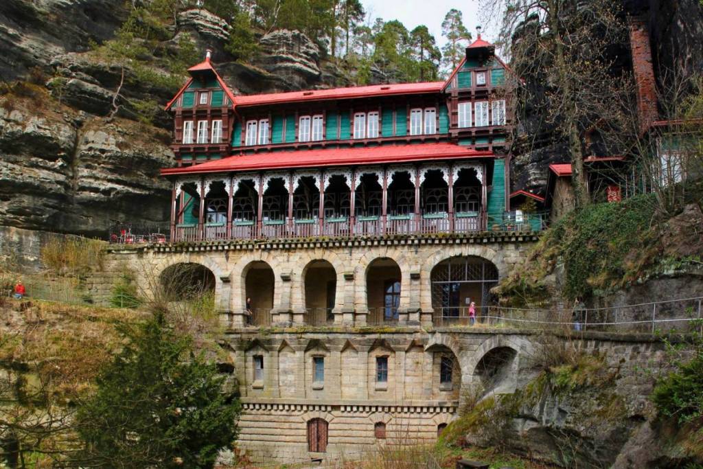 Het historische rode uitstapcafé direct in de rotswanden bij de Prebischtor, een hoogtepunt tijdens je weekendtrip naar Boheems Zwitserland.