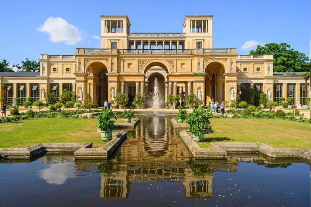 Het Orangerie-paleis in het Sanssouci-park op een zonnige dag met fonteinen, waterbassins en mediterrane kuipplanten.