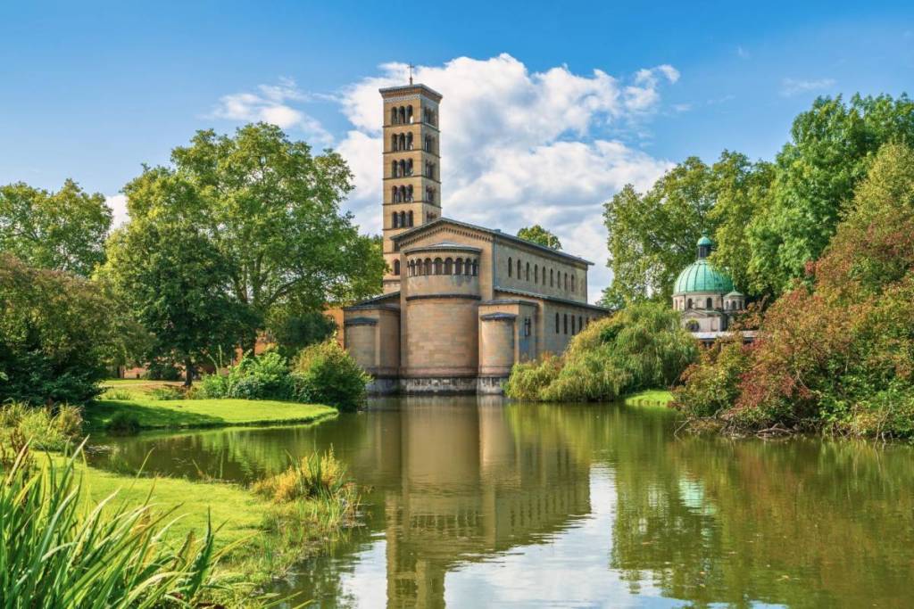 Schilderachtig totaalbeeld van de Vredeskerk en het Kaiser-Friedrich-mausoleum in de Marlygarten van het park Sanssouci in Potsdam aan het water.