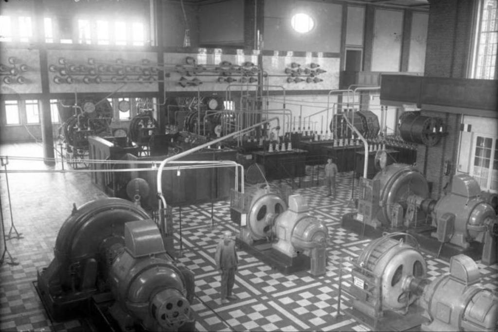 Historische zwart-witfoto uit het binnenste van het grote radiostation van Nauen: de uitgestrekte machinekamer met enorme generatoren en installaties voor de vroege telecommunicatie en morsetelegrafie.