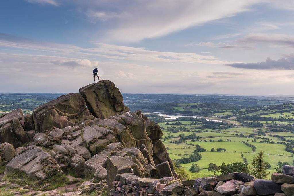 A climber at the roaches with a view over Tittisworth, Peak District National Par, one of the best day trips from Birmingham