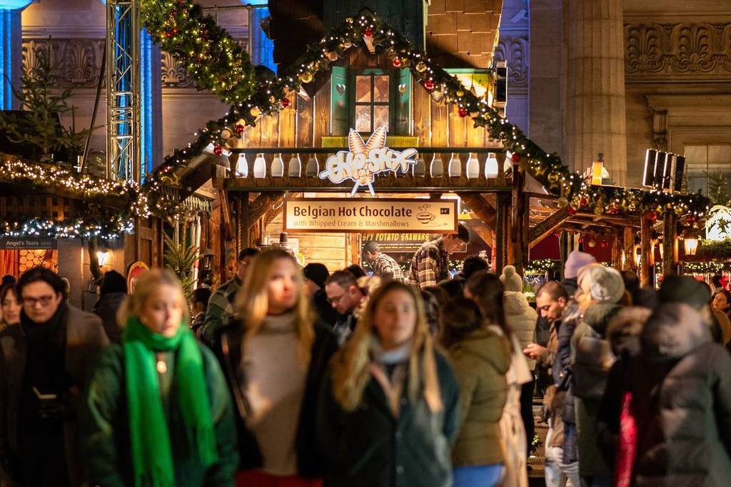 2023 11 29 UK, Edinburgh, Scotland, Christmas market in the Princes Street Gardens, Visitors crowd a festive chalet-style hot chocolate stall during the illuminated Christmas market in winter's chill.