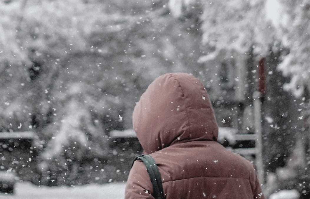 A person walking with their coat hood up through snow which is set to fall on Birmingham