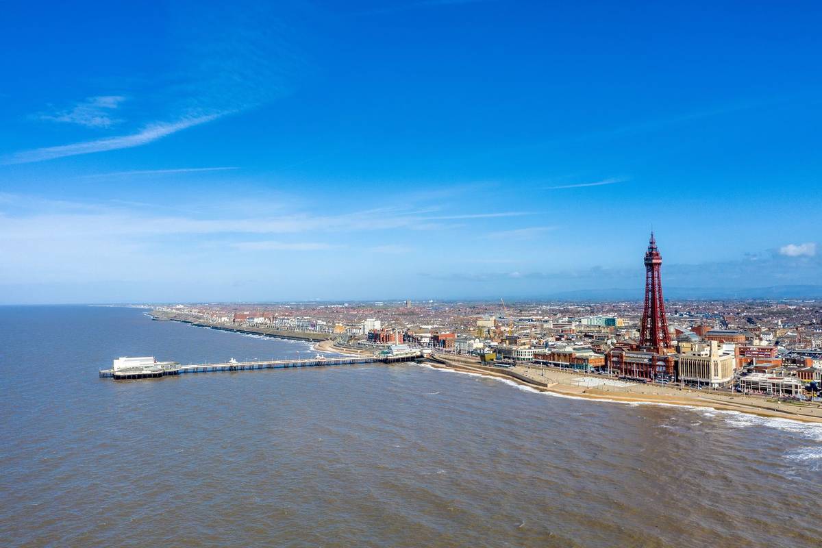 Aerial footage, drone view , of the famous Blackpool Tower and beach from the sky on a beautiful Summers day on one of Great Britains most popular holiday destinations, tourist attractions by the sea.  One of the best seaside towns near Birmingham.