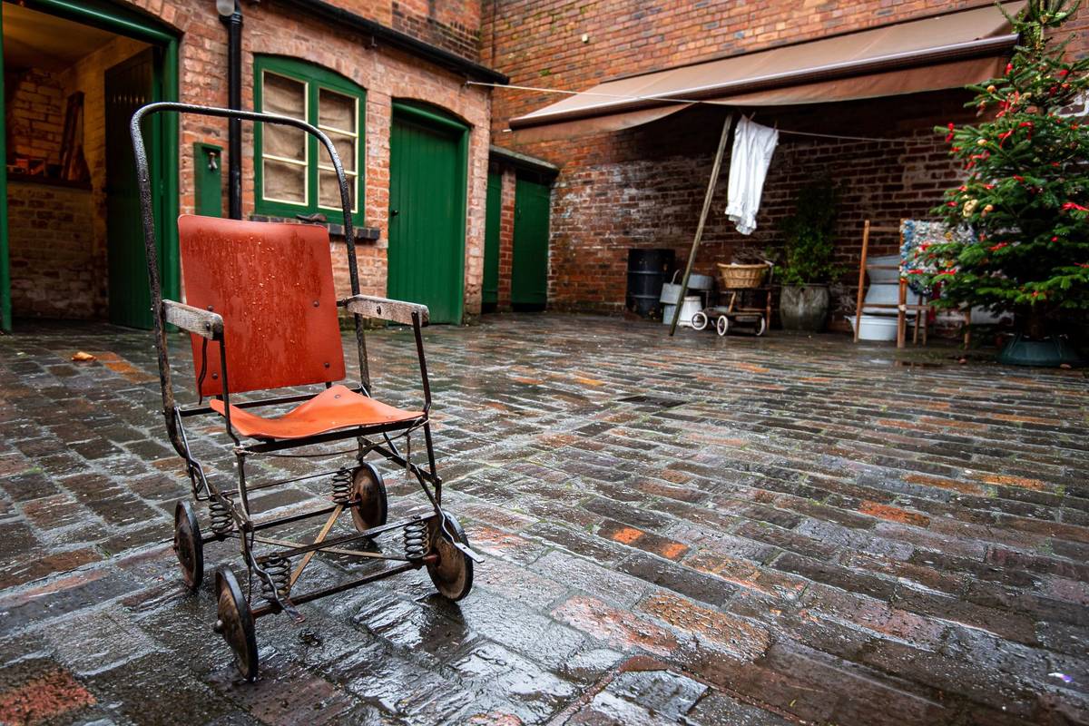 old vintage rusty metal frame orange handicap trolley in the courtyard surrounded by the back to back houses