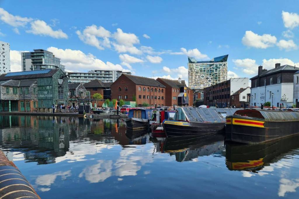 A body of water filled with lots of canal boats Central Birmingham near Brindley Place, on a sunny summer day.