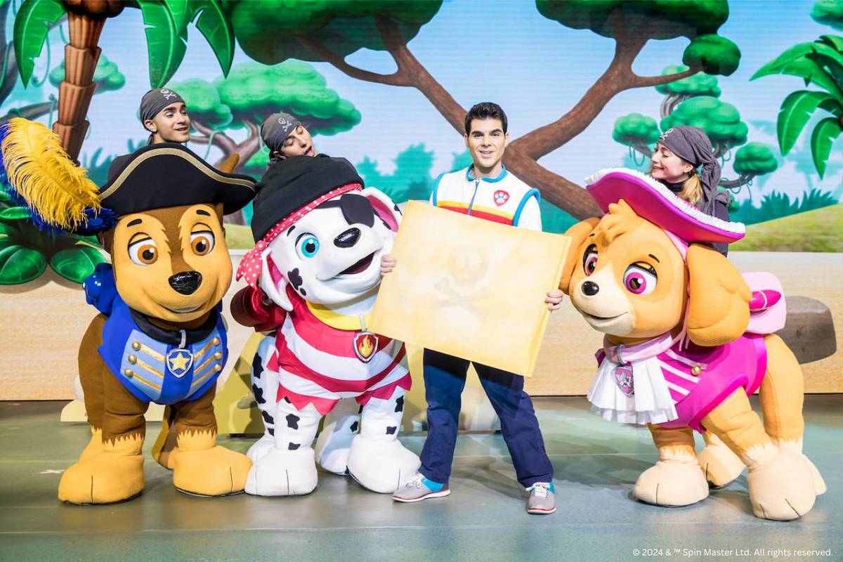 three paw patrol characters look at a map held by Ryder during the Paw Patrol Live stage show