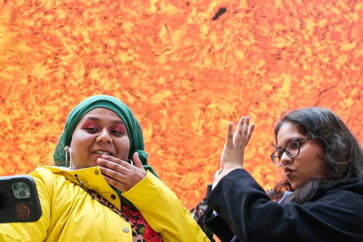 two-visitors-taking-selfies-in-front-of-helios-at-osterley