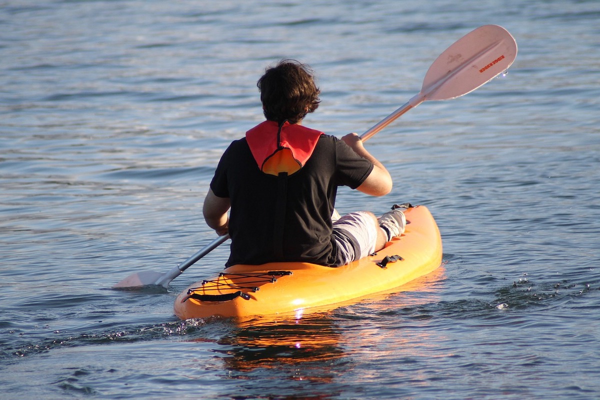 a man kayaks away across the water
