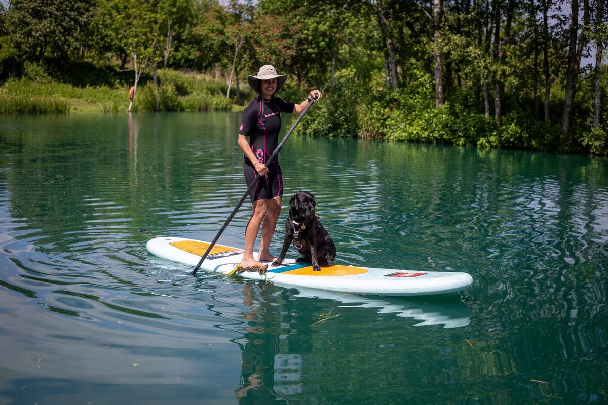 A woman paddleboarding with her dog