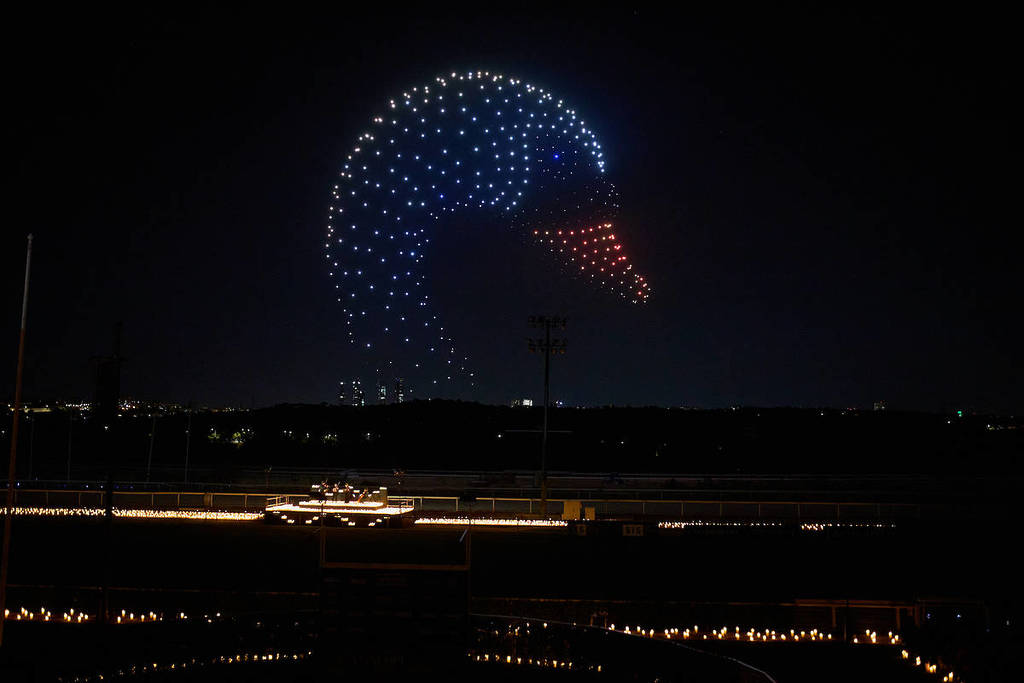 A giant swan created by thousands of drones lights up the skies above a crowd