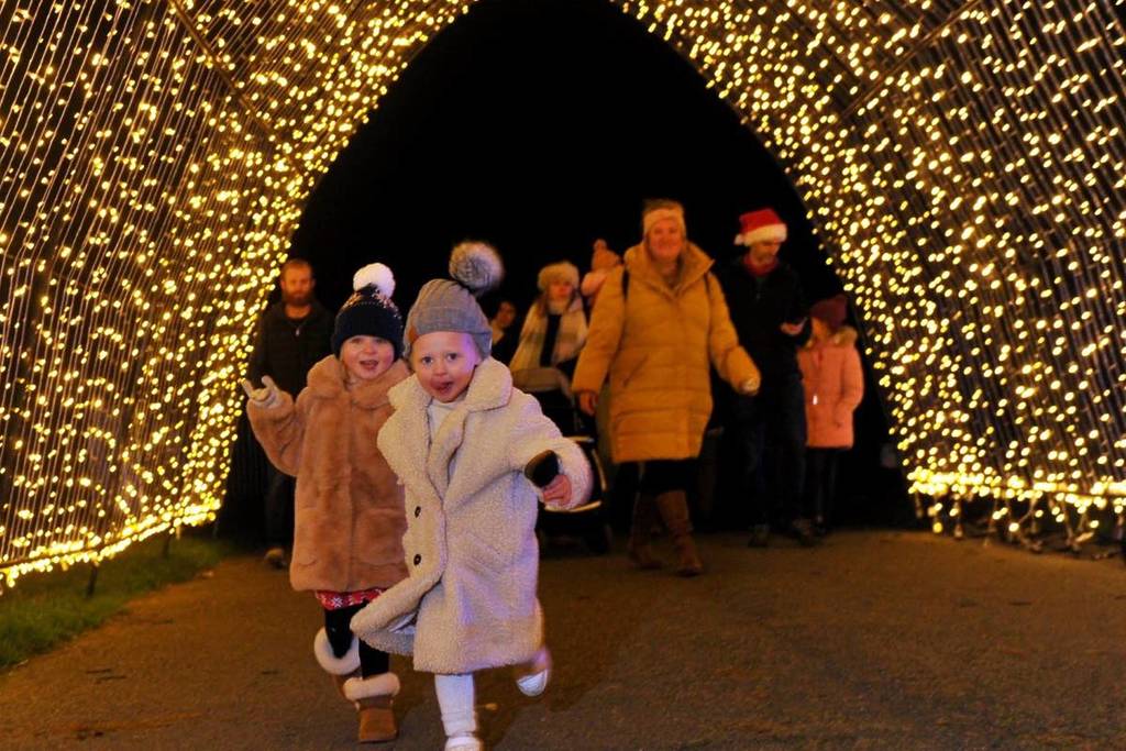 Children running through a tunnel of lights at Winter Glow