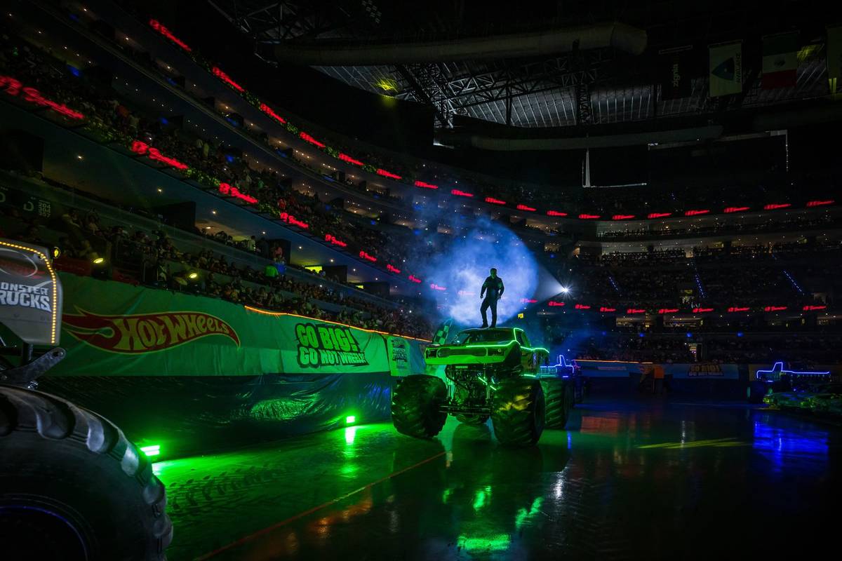 A driver illuminated atop of a monster truck