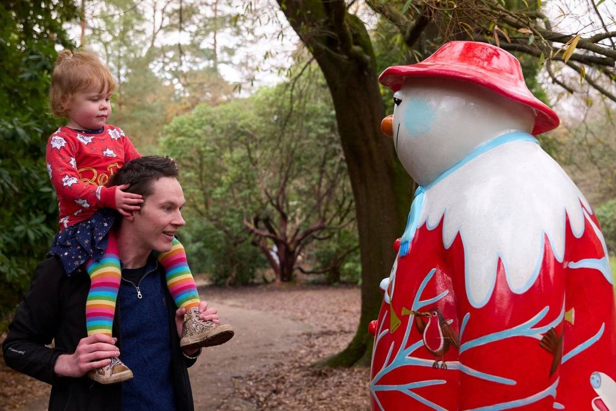 A father and child looking at a Snowman sculpture