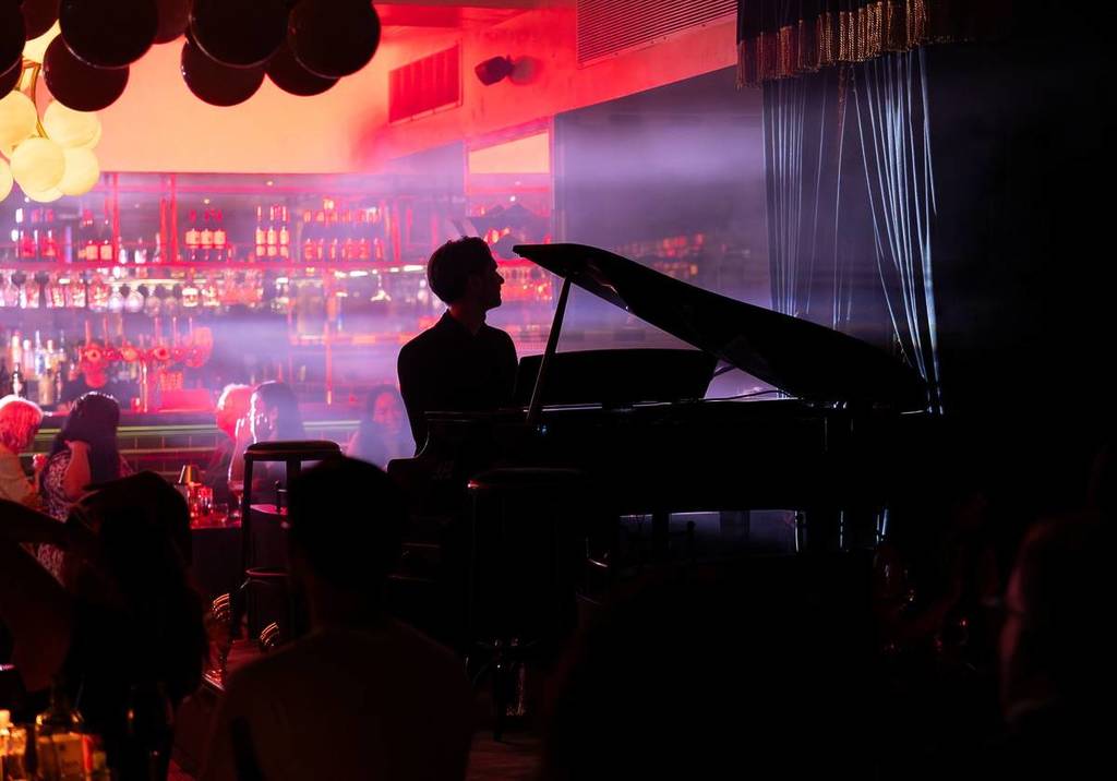 A silhouette of a man at a piano at Downstairs at The Grand