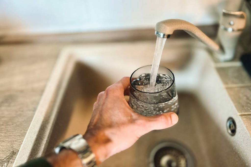 A kitchen tap filling up a glass with water