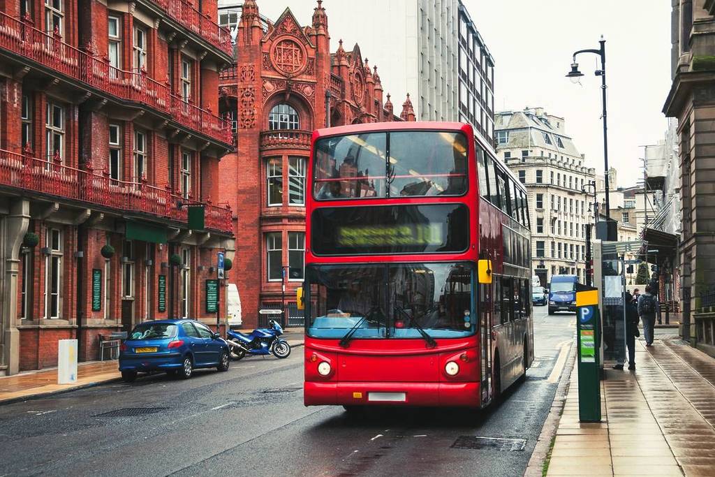 Red double-decker bus at the street of Birmingham, UK. Old building of the historical part of the city. Cars, famous restaurants and pubs