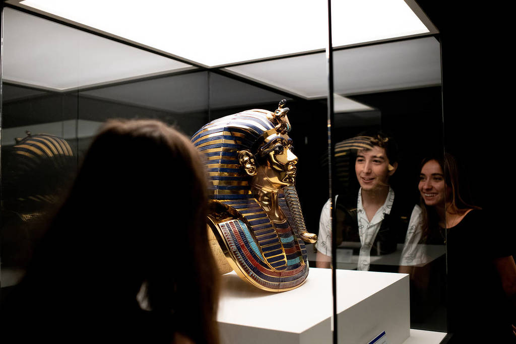 visitors of the Tutankhamun: The Immersive Exhibition looking at the artefact - Tutankhamun's mask