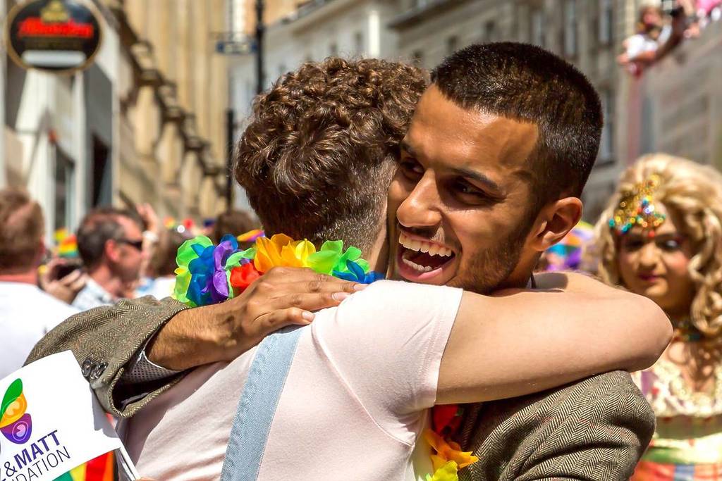 Birmingham, UK - May 25, 2019 - An Asian and White male show delight as they hug each other during the Pride celebrations in Birmingham City centre.