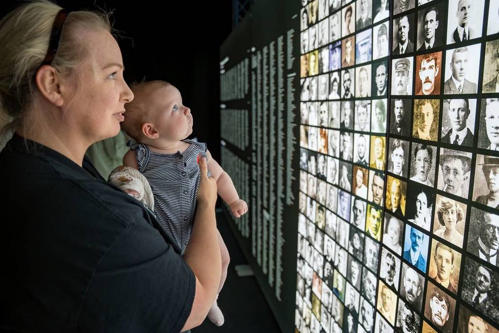 A woman and baby looking at pictures of Titanic passengers