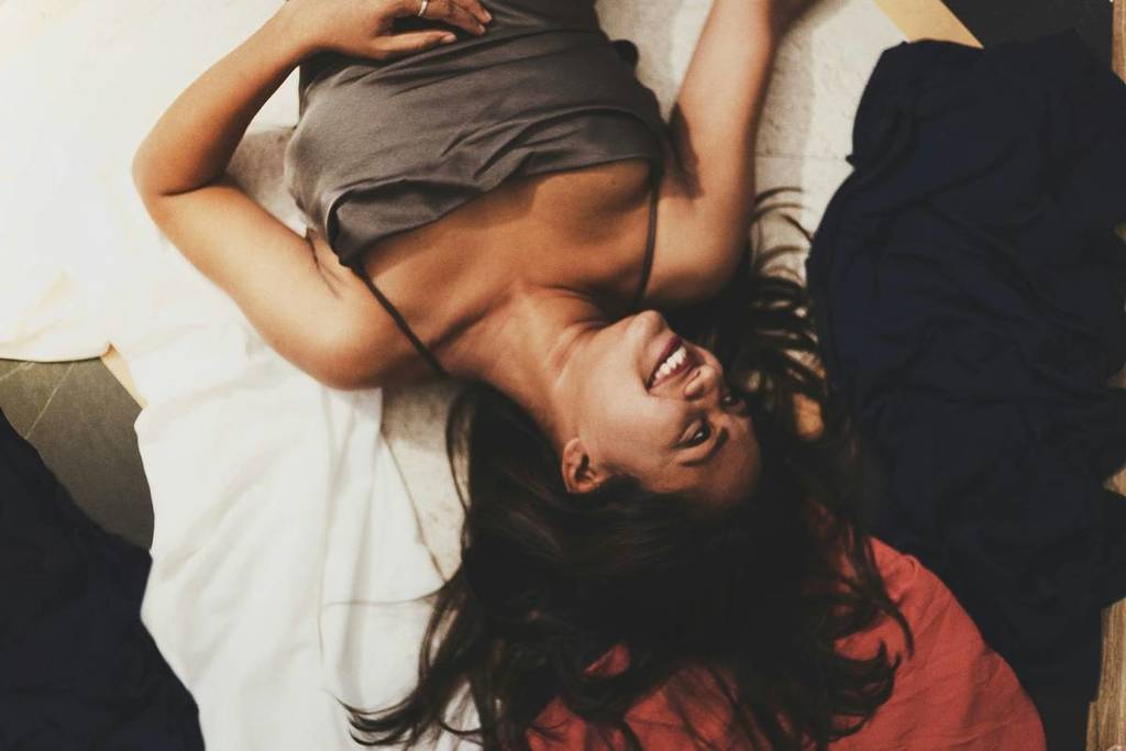 A woman lying on a bed upside down