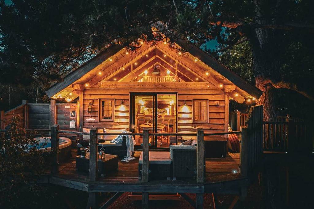 The outside of the Orchard Treehouse at night, lit up