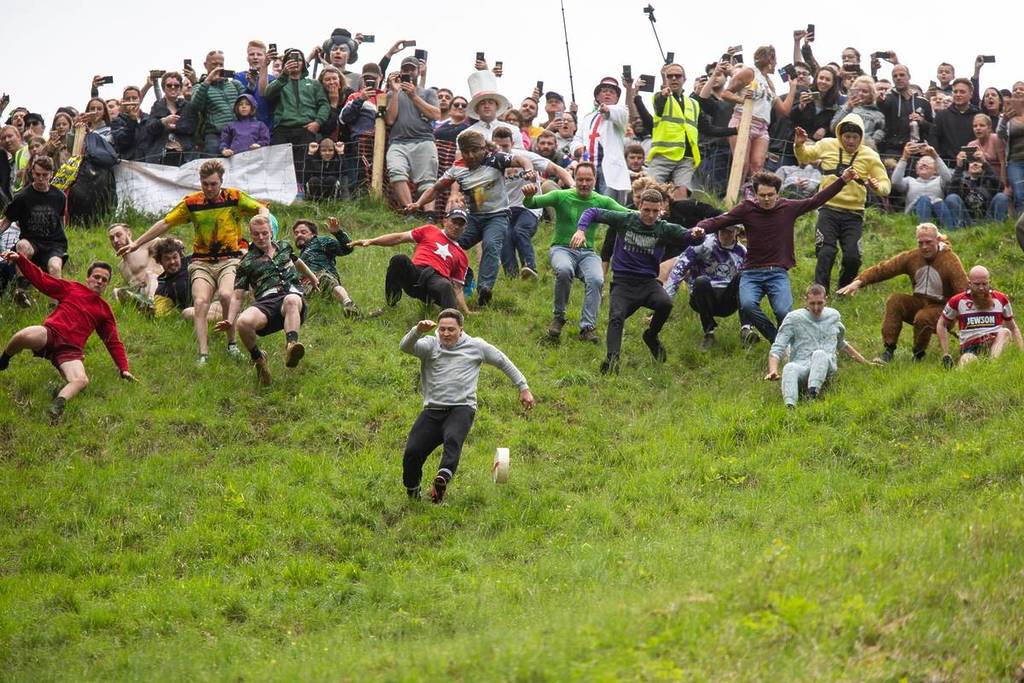 Brockworth, England, UK, May 27th 2019. Eventual winner (front left) Max McDougall chases the cheese during the annual Spring bank holiday cheese-rolling event at Cooper's Hill near Gloucester.