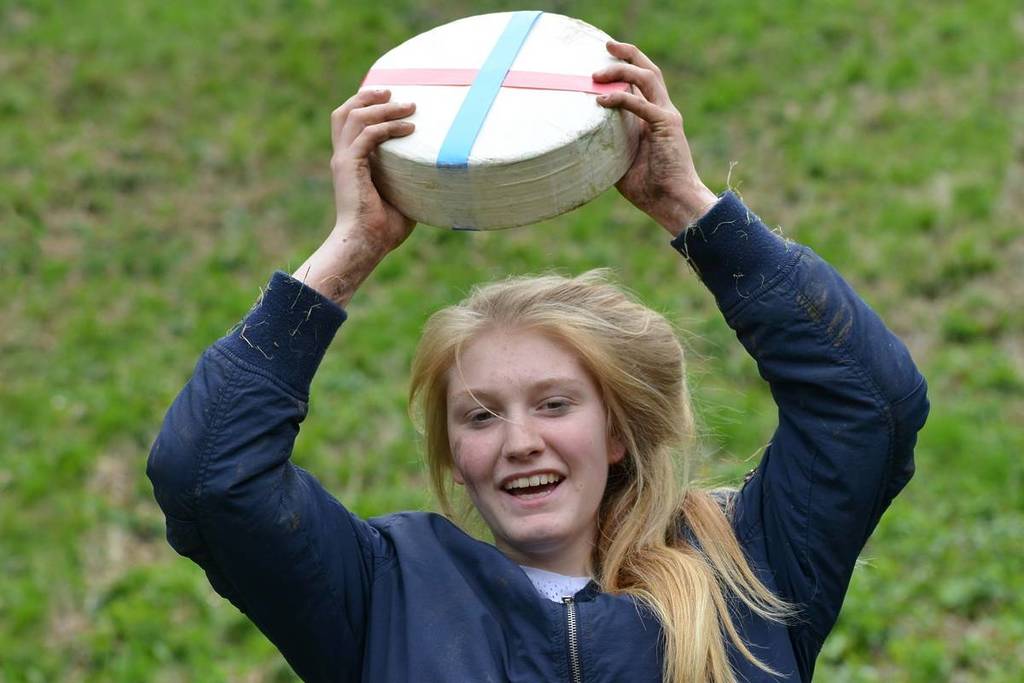 A competitor holds a cheese after winning the traditional cheese rolling races on Cooper's Hill on May 25, 2015 in Brockworth, UK. Thousands attended the unsanctioned annual event.