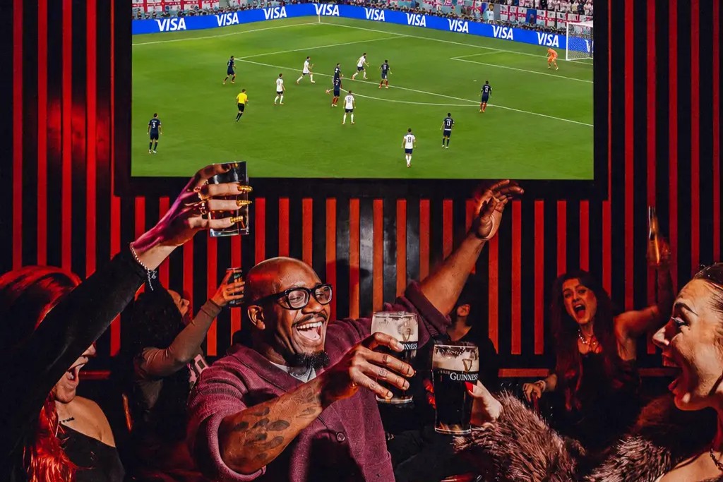 People drinking at Roxy Ball Room with the World Cup on a TV screen in the background