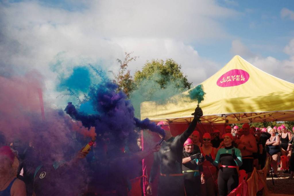 People in wetsuits letting off coloured flares for an event at Watersedge