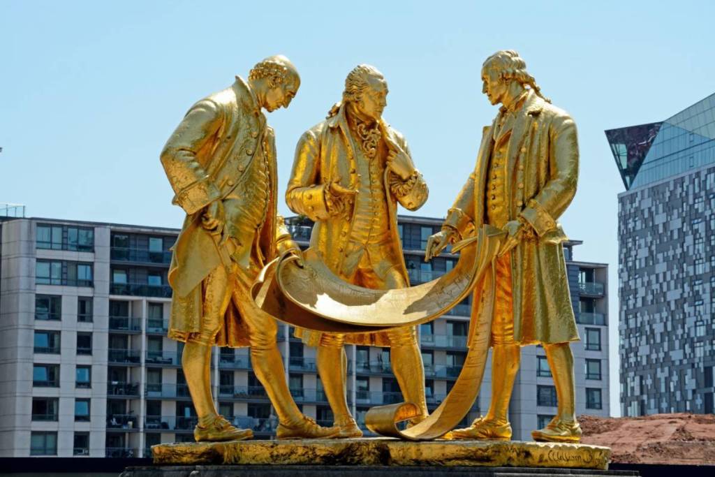 BIRMINGHAM, UNITED KINGDOM - JUNE 6, 2016 - View of the golden Boulton, Watt and Murdoch statue in Centenary Square, Birmingham, England, UK, Western Europe, June 6, 2016.