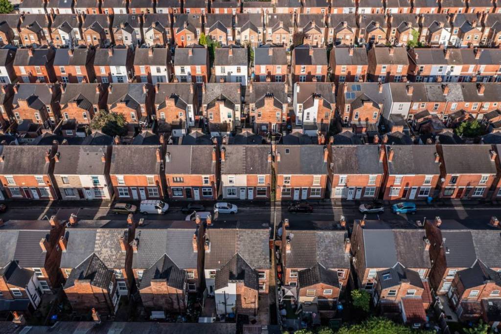 An aerial view above the drab rooftops of run down back to back terraced houses on a large residential estate in the North of England