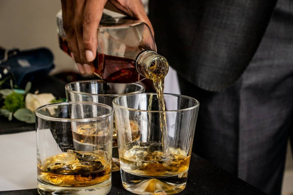 Cocktail being poured into three glasses