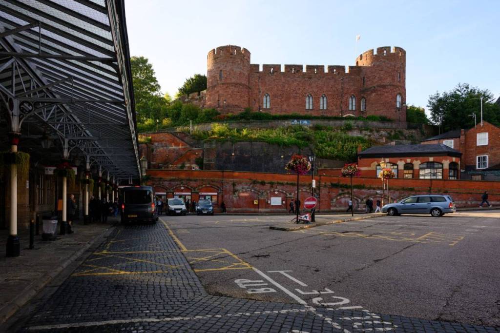 Shrewsbury, England, UK - September 9, 2025; Parking lot in front of Shrewsbury Railway Station with canopy under historic castle