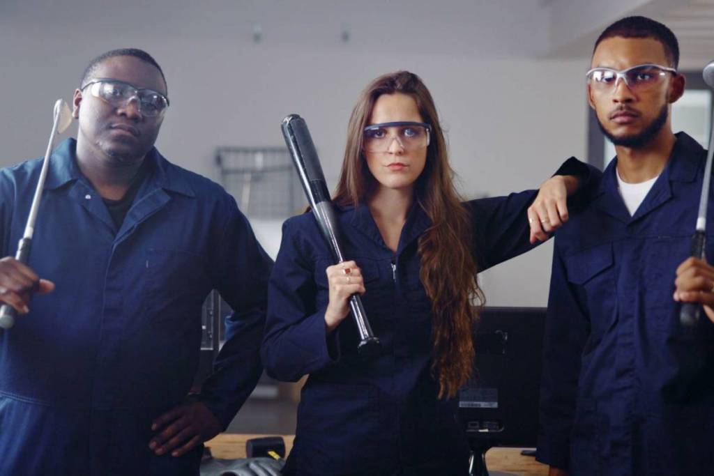 Portrait, weapon and friends in rage room for anger management, cathartic therapy and stress relief. Bat, safety gear and golf club with people in smash center for demolition, break and vandalism