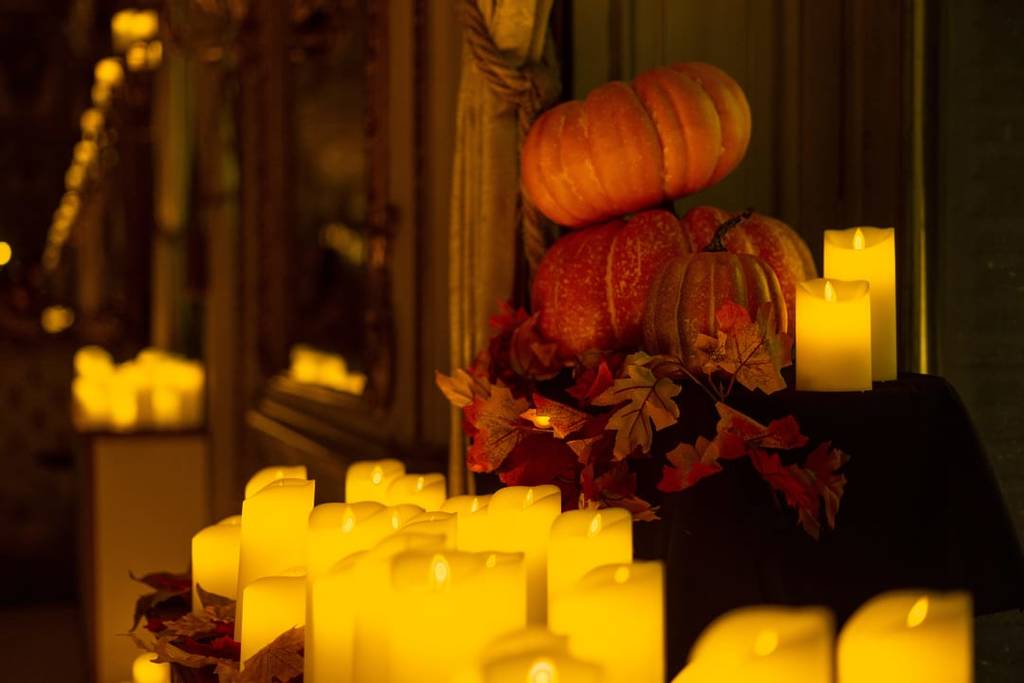Two pumpkins behind candles at a Halloween Candlelight concert. 