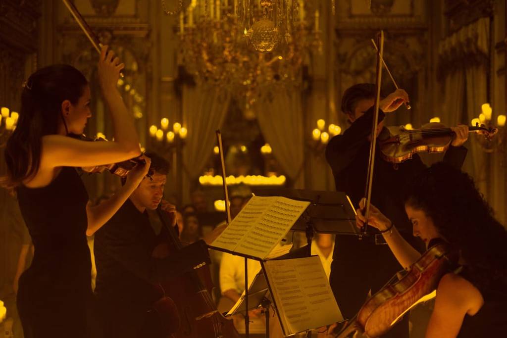 A string quartet play in front of flickering candles at Halloween Candlelight, 