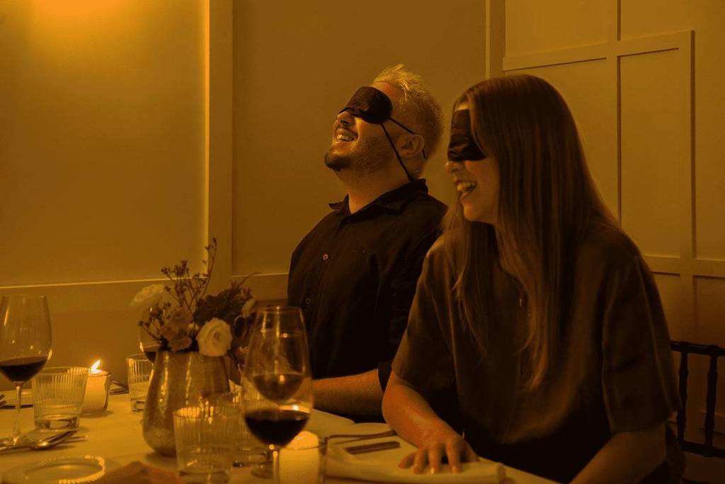 man and woman laugh in blindfolds as part of dining in the dark