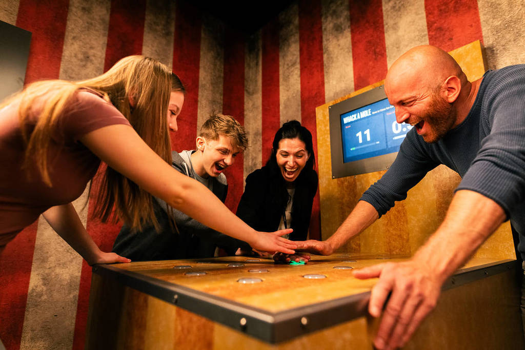 A family of 4 lean over a game at Prison Island.