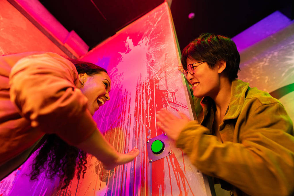 A young man and woman prepare to press a green buzzer at Prison Island.