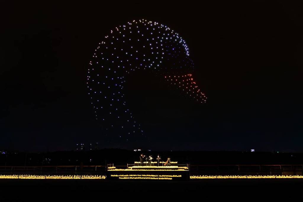 An image of a swan's head created by drones is pictured in the sky above a candlelit orchestra at DroneArt Show.