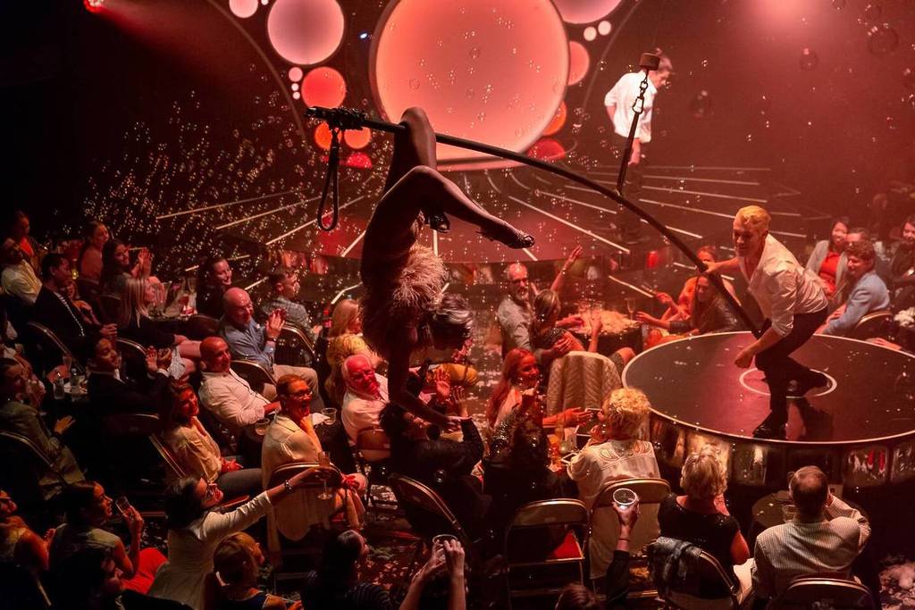 A wide shot of a Blanc de Blanc performer hanging over the crowd as bubbles fill the air